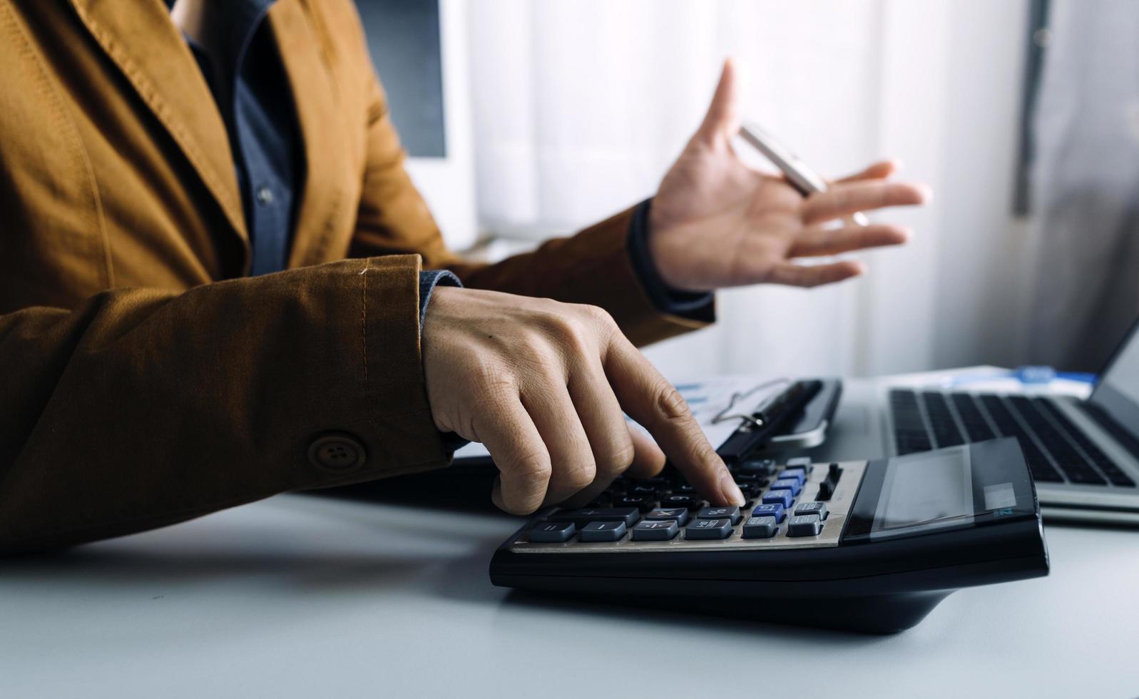 Business accounting concept, Business man using calculator with computer laptop, budget and loan paper in office. photo