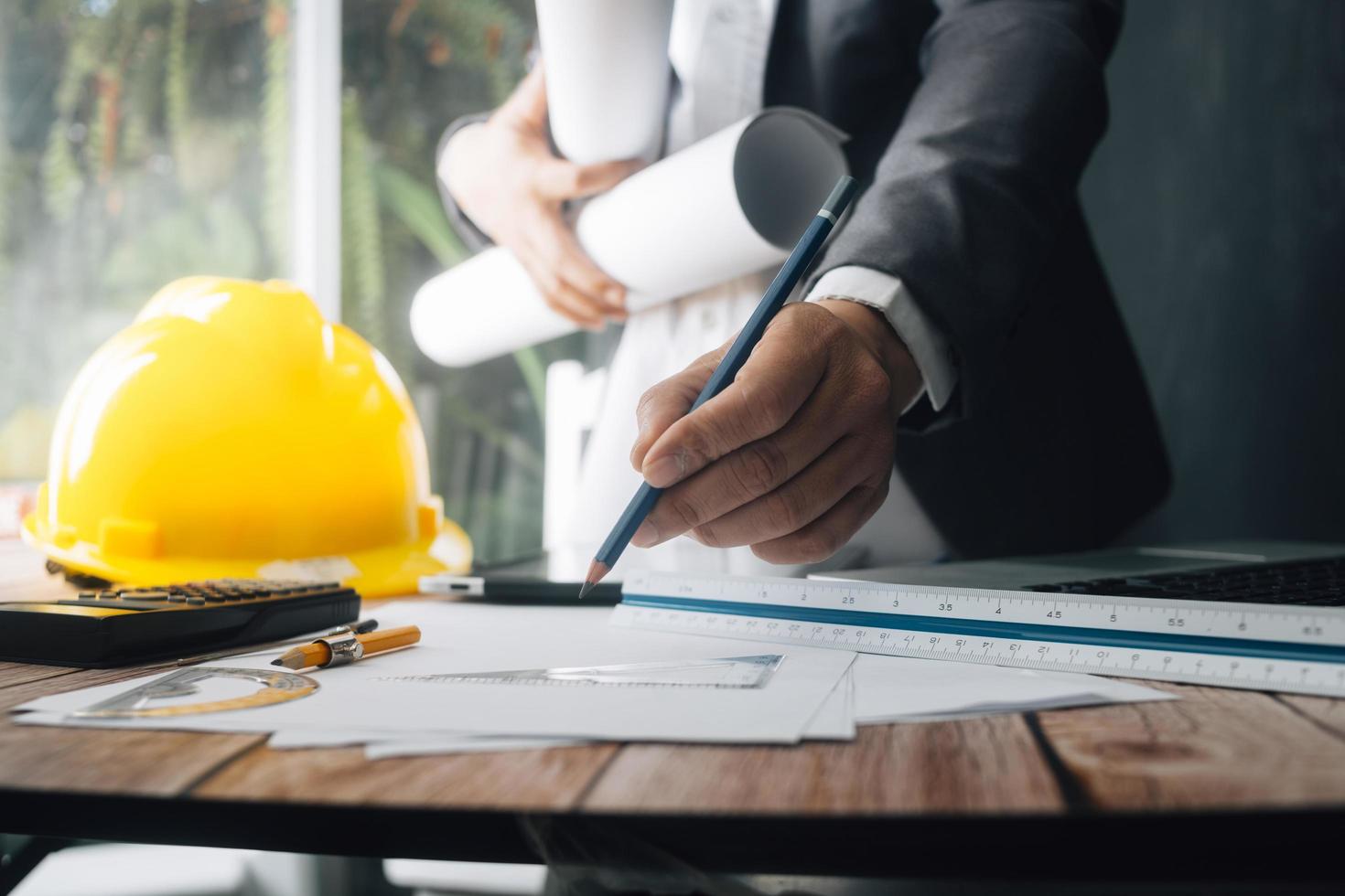 Two colleagues discussing data working and tablet, laptop with on on architectural project at construction site at desk in office photo