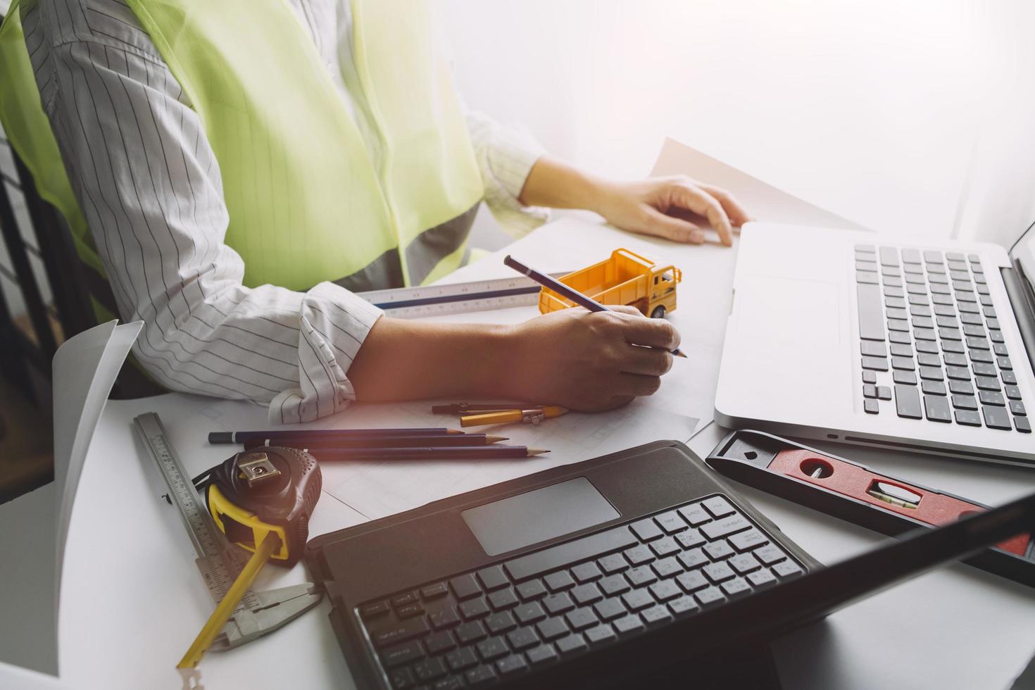 Two colleagues discussing data working and tablet, laptop with on on architectural project at construction site at desk in office photo