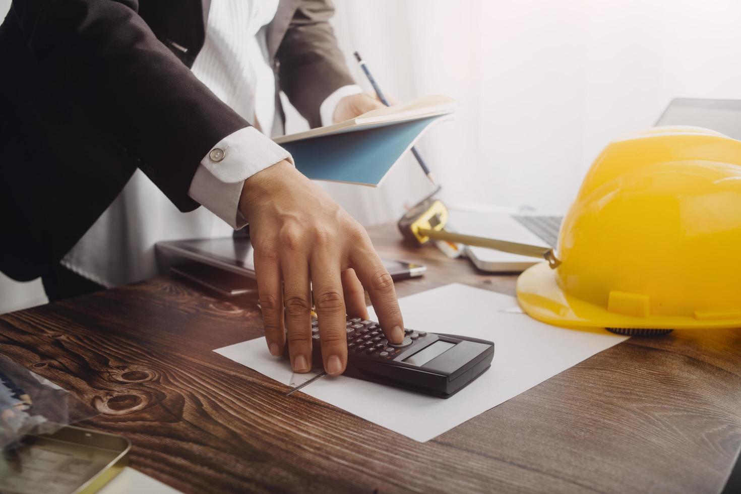 business hand working and laptop with on on architectural project at construction site at office desk in office photo