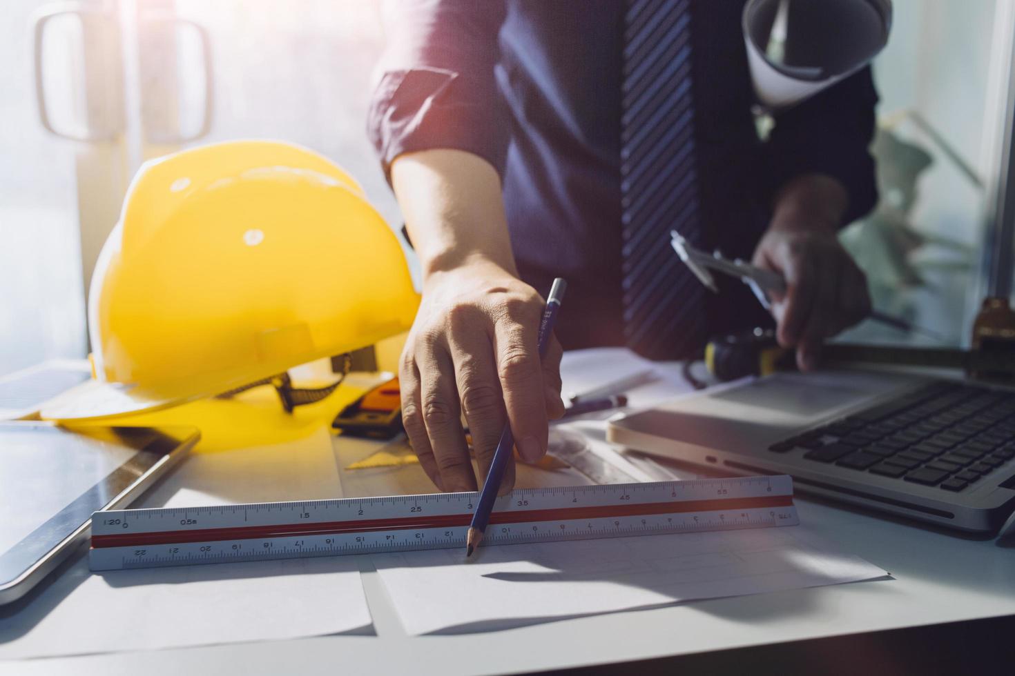 Two colleagues discussing data working and tablet, laptop with on on architectural project at construction site at desk in office photo