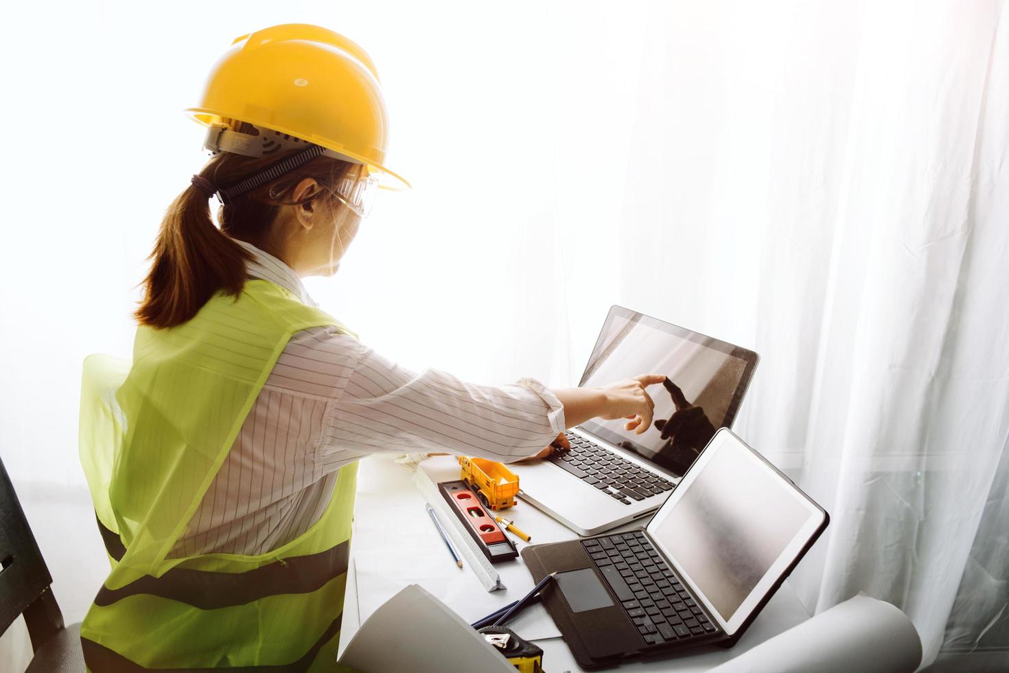 Two colleagues discussing data working and tablet, laptop with on on architectural project at construction site at desk in office photo