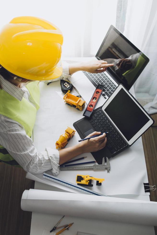 business hand working and laptop with on on architectural project at construction site at office desk in office photo