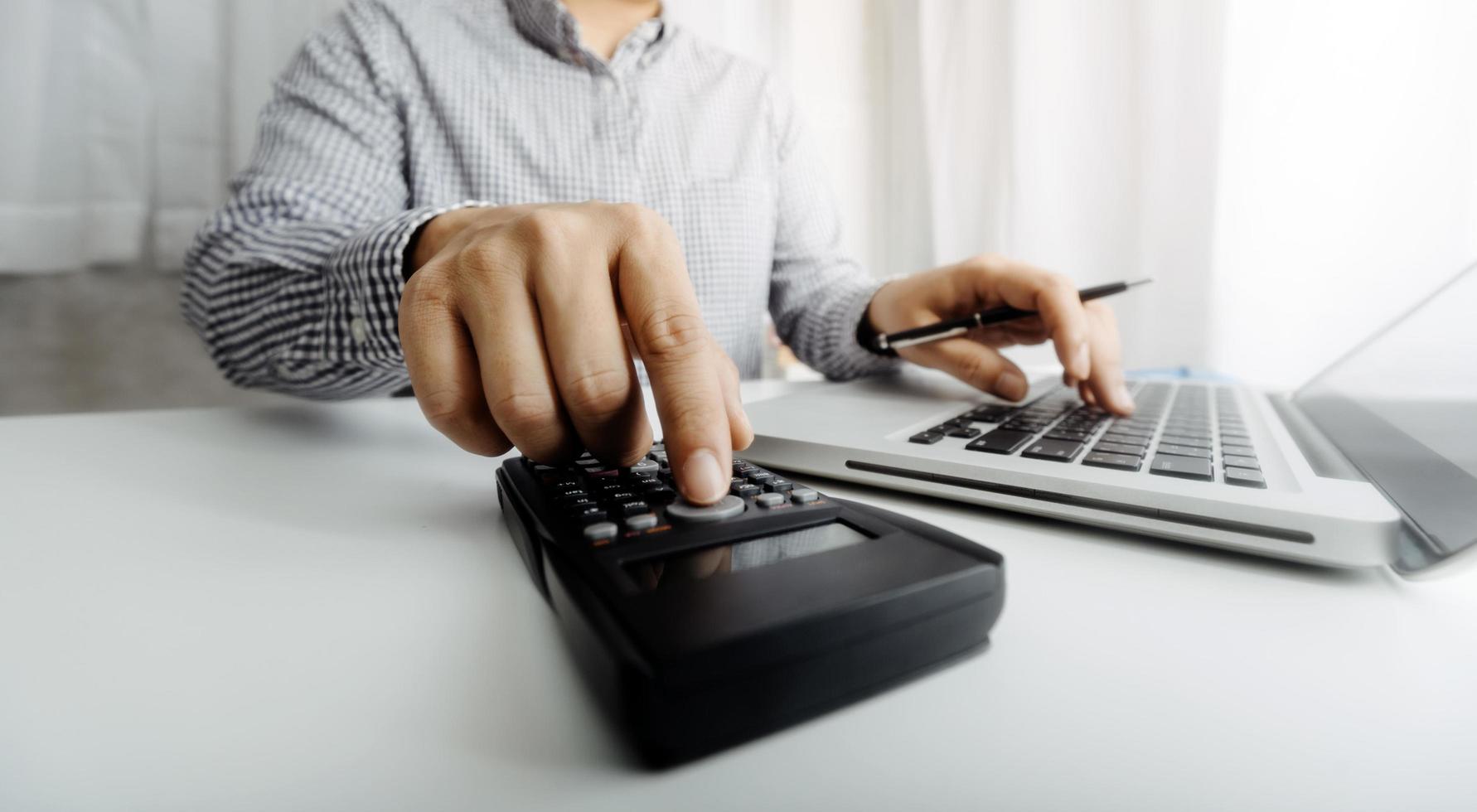 Business accounting concept, Business man using calculator with computer laptop, budget and loan paper in office. photo