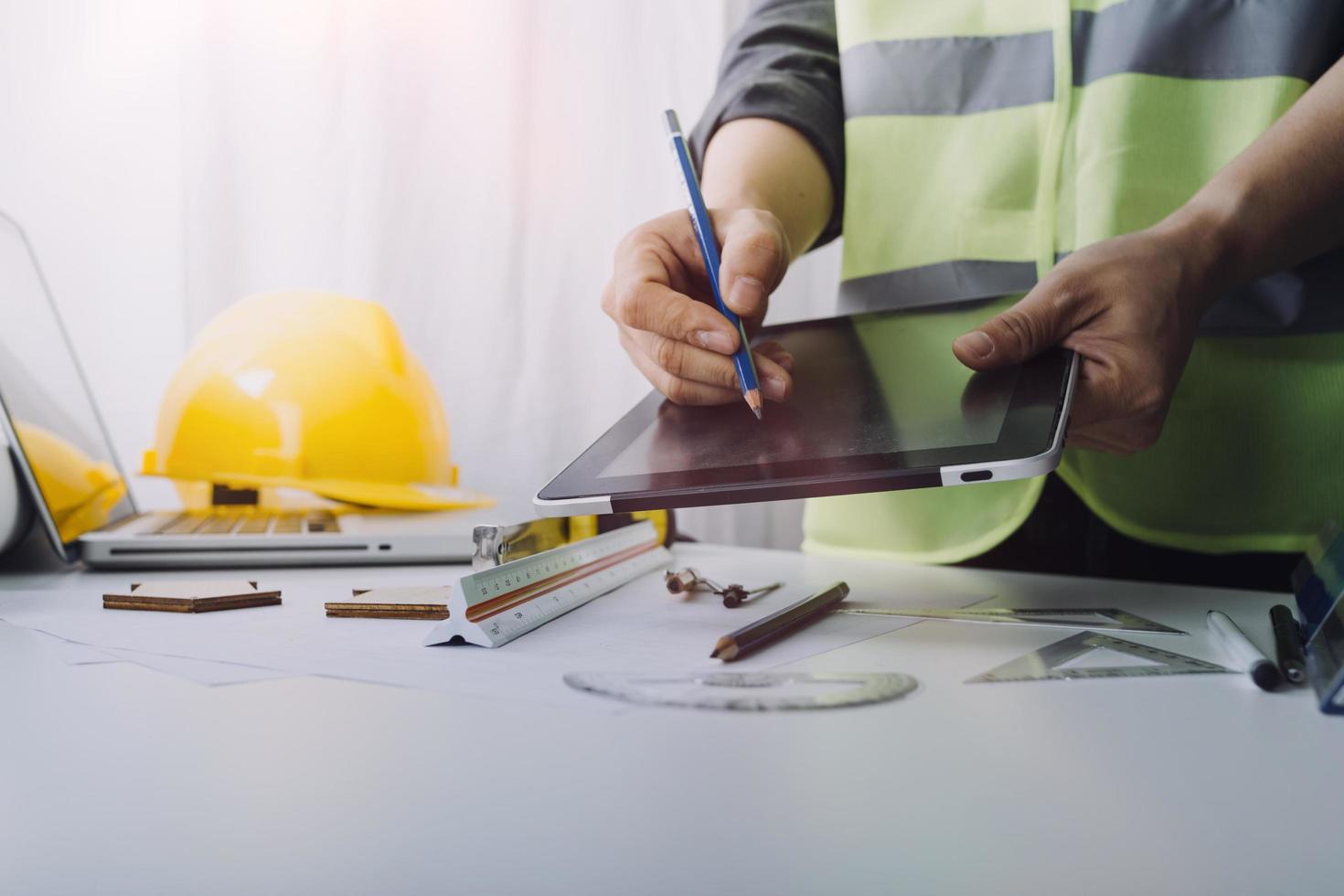 Two colleagues discussing data working and tablet, laptop with on on architectural project at construction site at desk in office photo