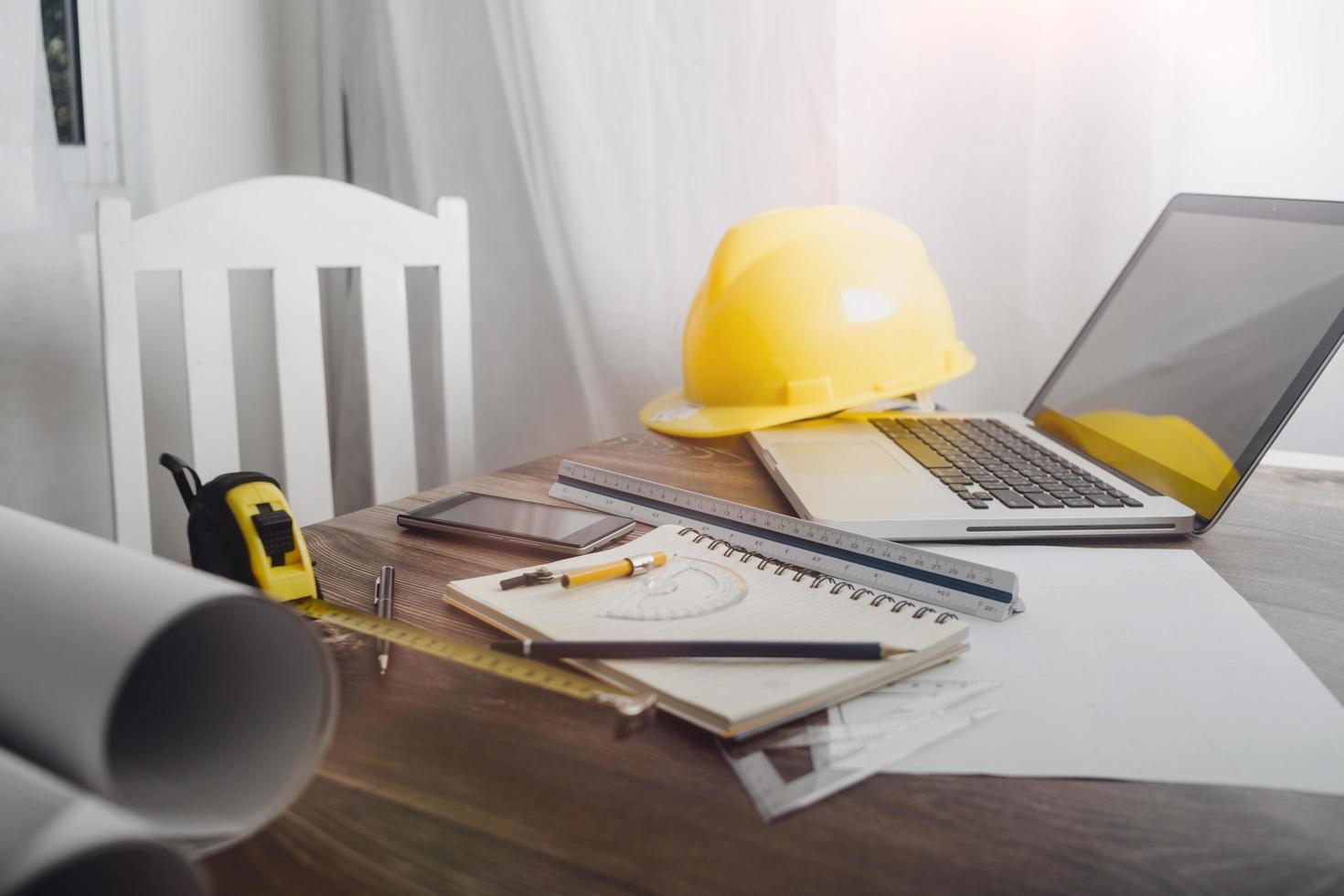 Two colleagues discussing data working and tablet, laptop with on on architectural project at construction site at desk in office photo