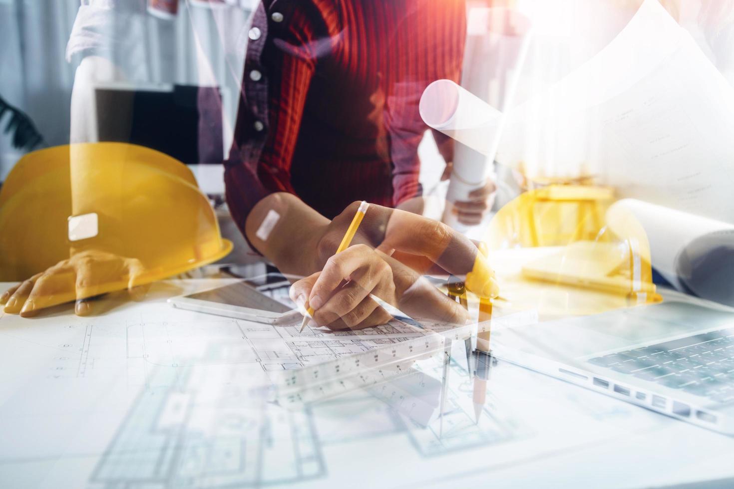 Two colleagues discussing data working and tablet, laptop with on on architectural project at construction site at desk in office photo