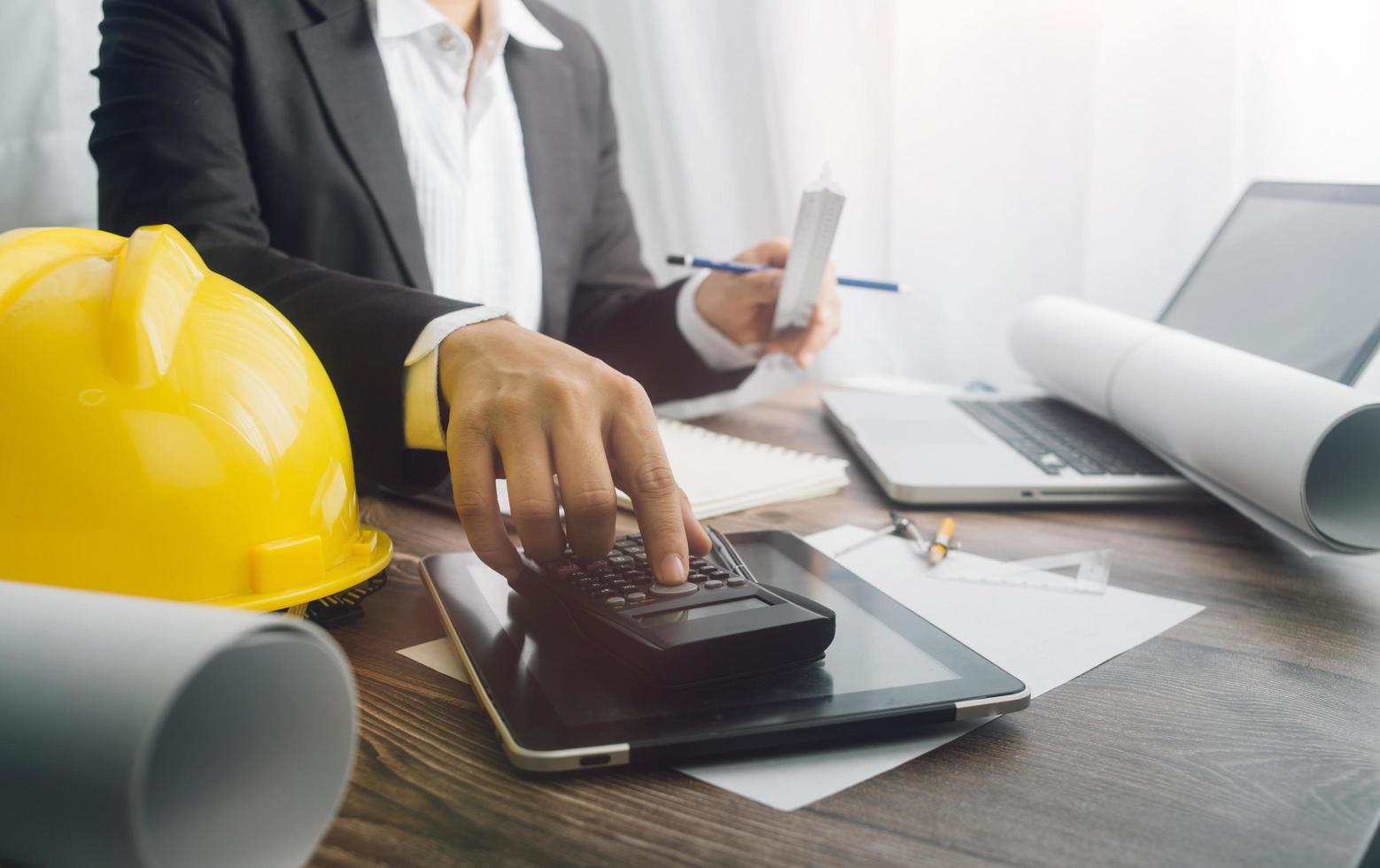 Two colleagues discussing data working and tablet, laptop with on on architectural project at construction site at desk in office photo
