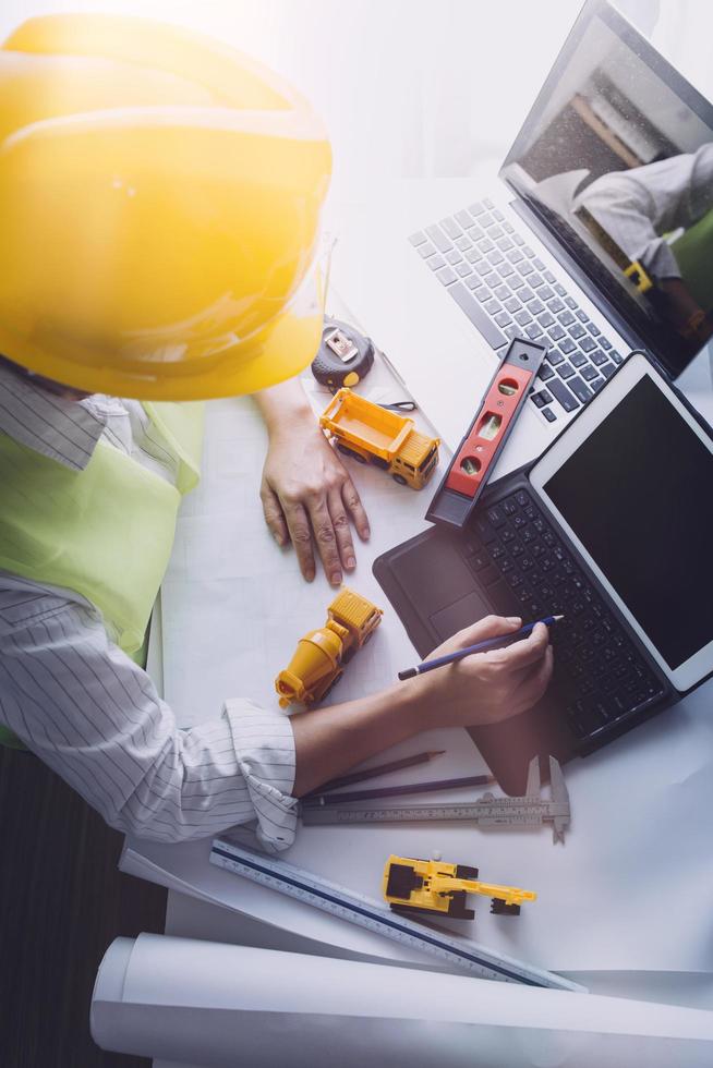Two colleagues discussing data working and tablet, laptop with on on architectural project at construction site at desk in office photo