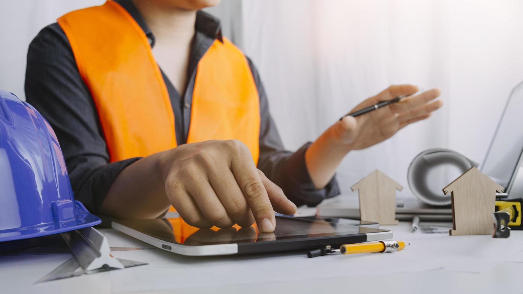Two colleagues discussing data working and tablet, laptop with on on architectural project at construction site at desk in office photo