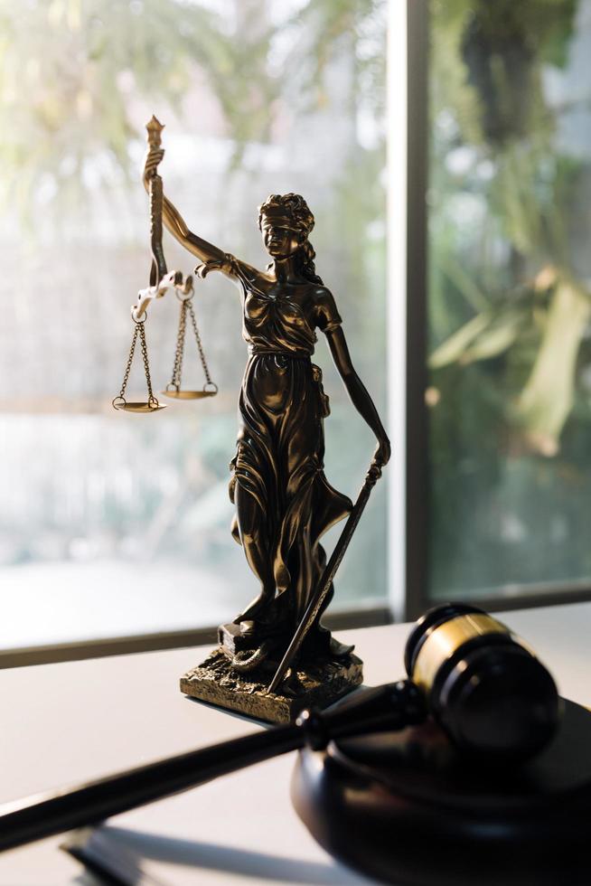 Justice and law concept.Male judge in a courtroom with the gavel, working with, computer and docking keyboard, eyeglasses, on table in morning light photo