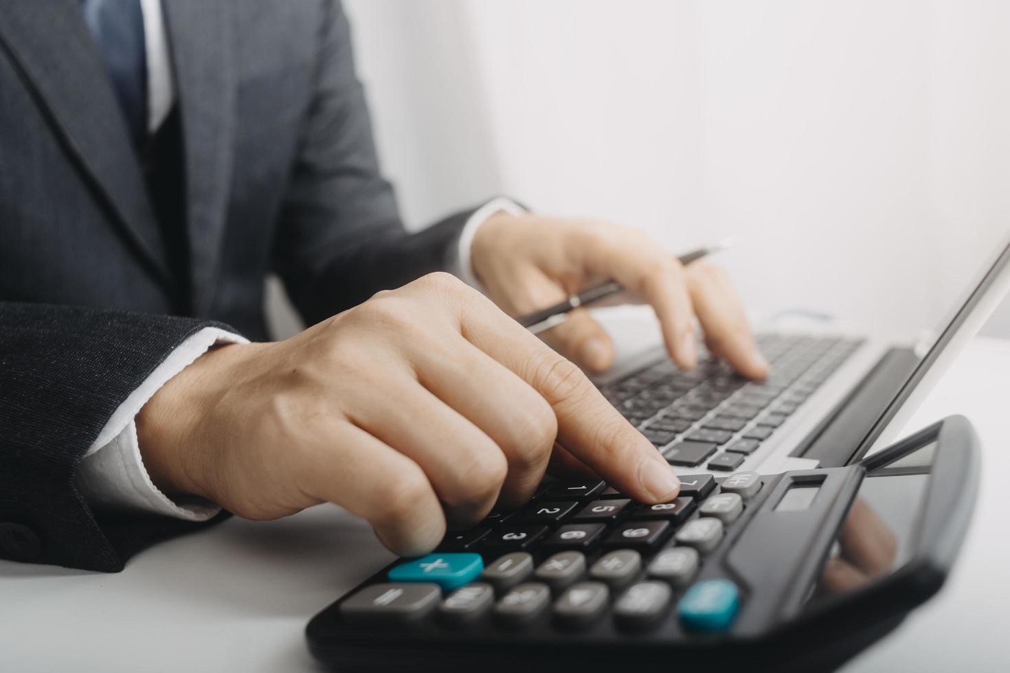 Business accounting concept, Business man using calculator with computer laptop, budget and loan paper in office. photo