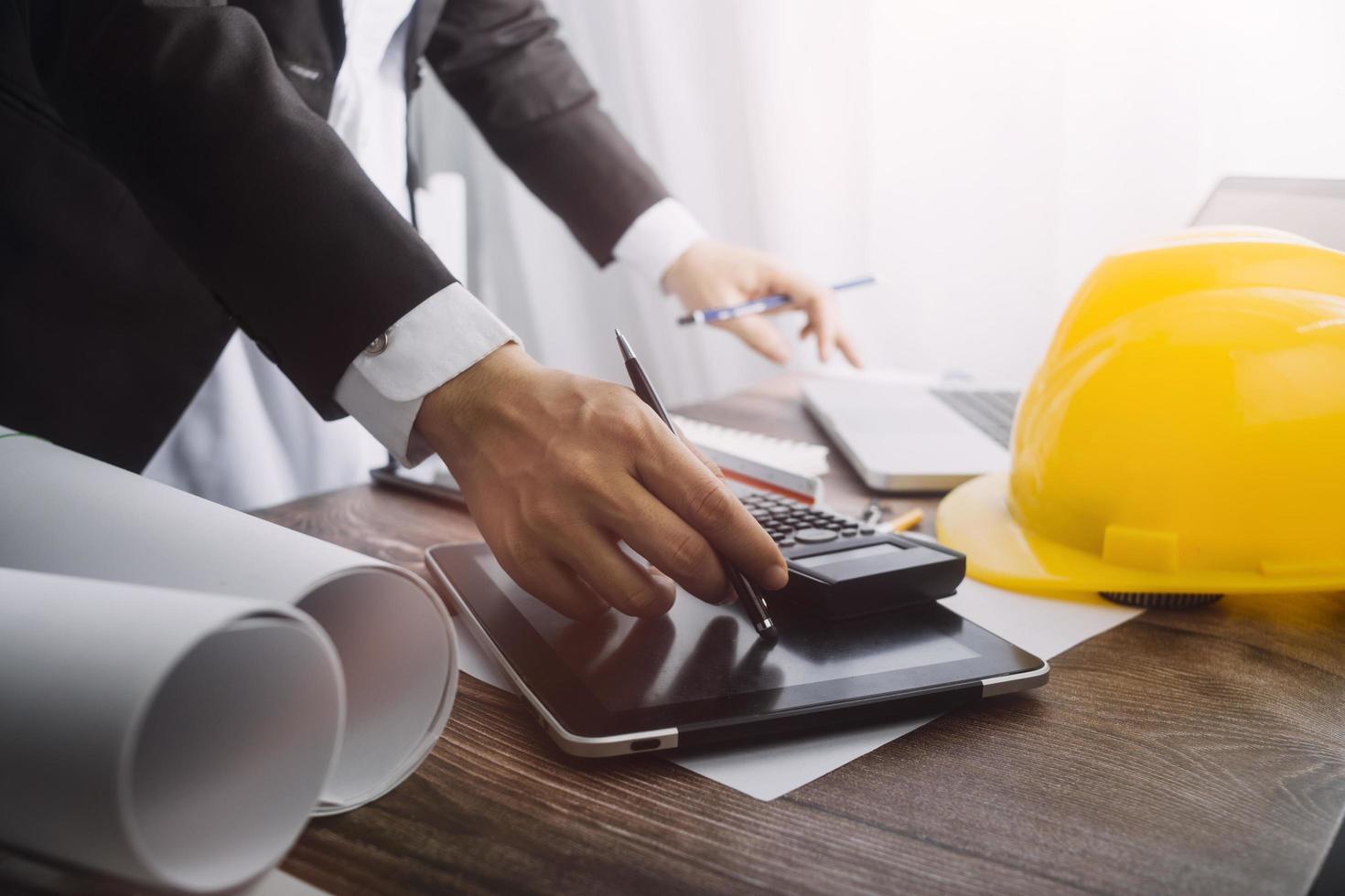 business hand working and laptop with on on architectural project at construction site at office desk in office photo