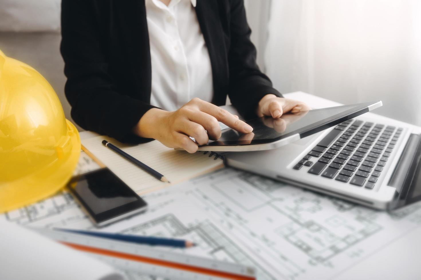 Two colleagues discussing data working and tablet, laptop with on on architectural project at construction site at desk in office photo