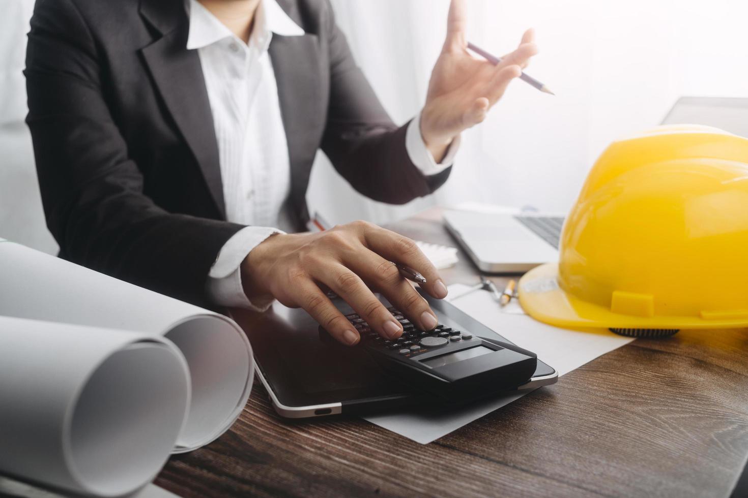 business hand working and laptop with on on architectural project at construction site at office desk in office photo