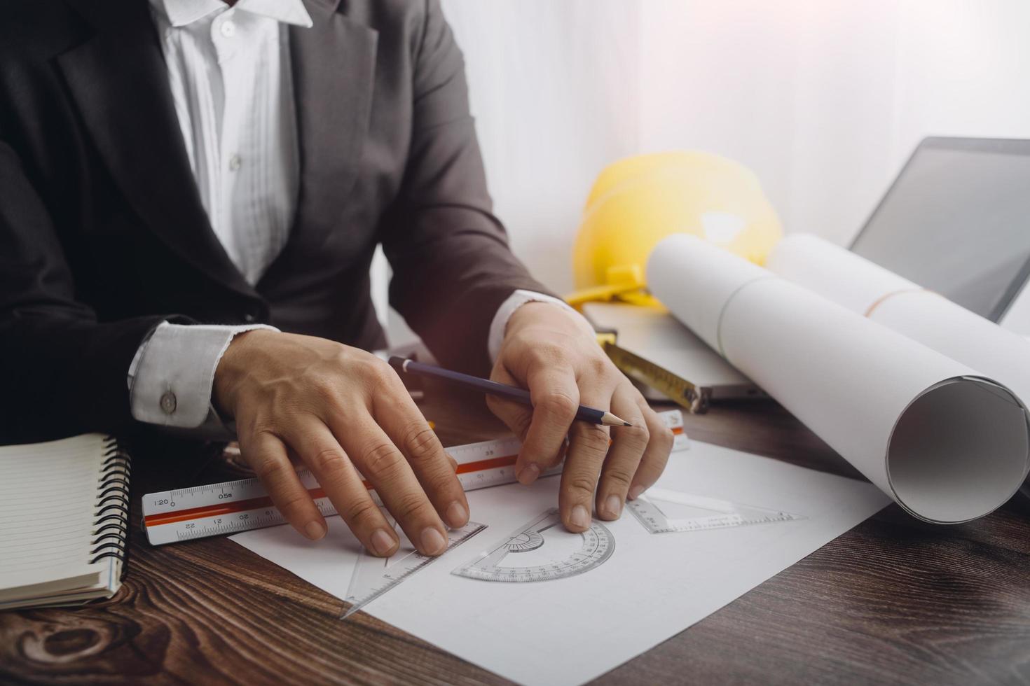 Dos colegas discutiendo el trabajo de datos y una tableta, un portátil con un proyecto arquitectónico en el sitio de construcción en un escritorio en la oficina foto