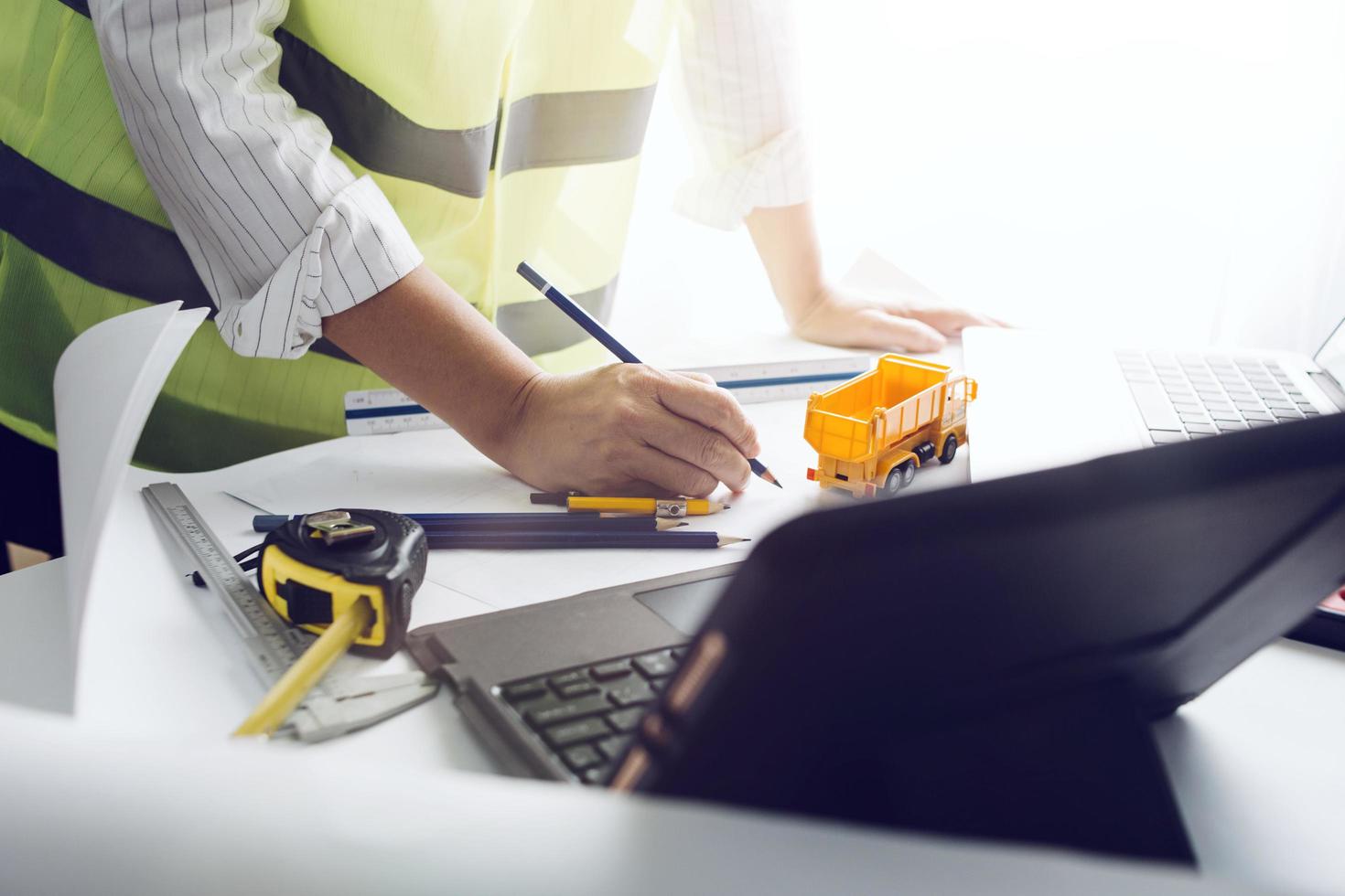business hand working and laptop with on on architectural project at construction site at office desk in office photo