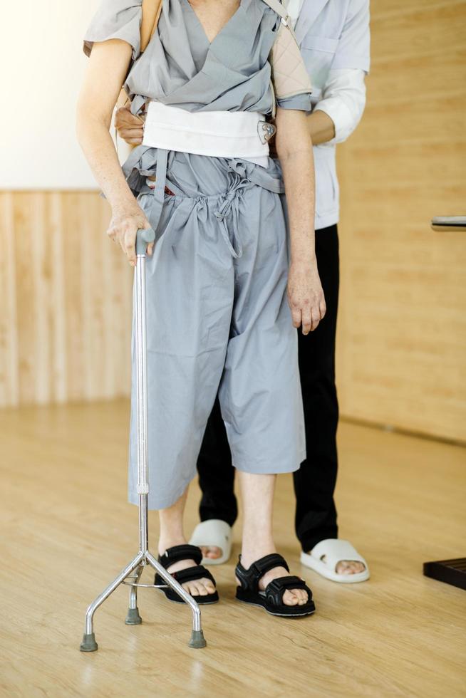 Physiotherapist helping senior woman with walker at remedial gymnastics photo