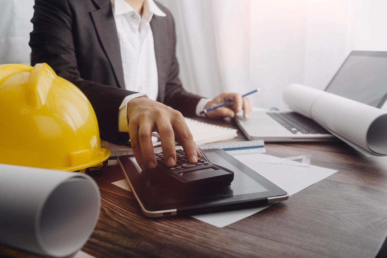 Two colleagues discussing data working and tablet, laptop with on on architectural project at construction site at desk in office photo