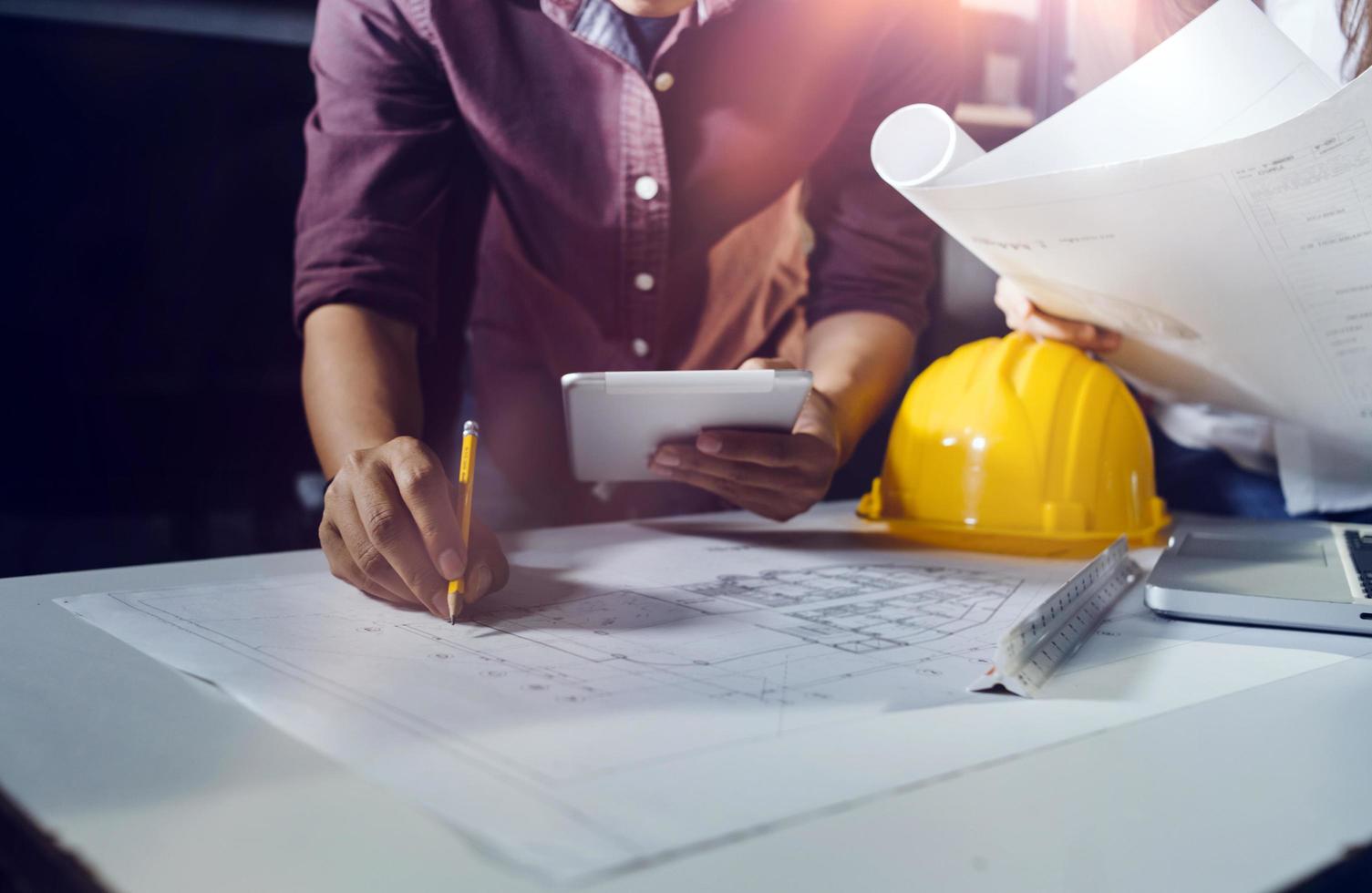 Two colleagues discussing data working and tablet, laptop with on on architectural project at construction site at desk in office photo
