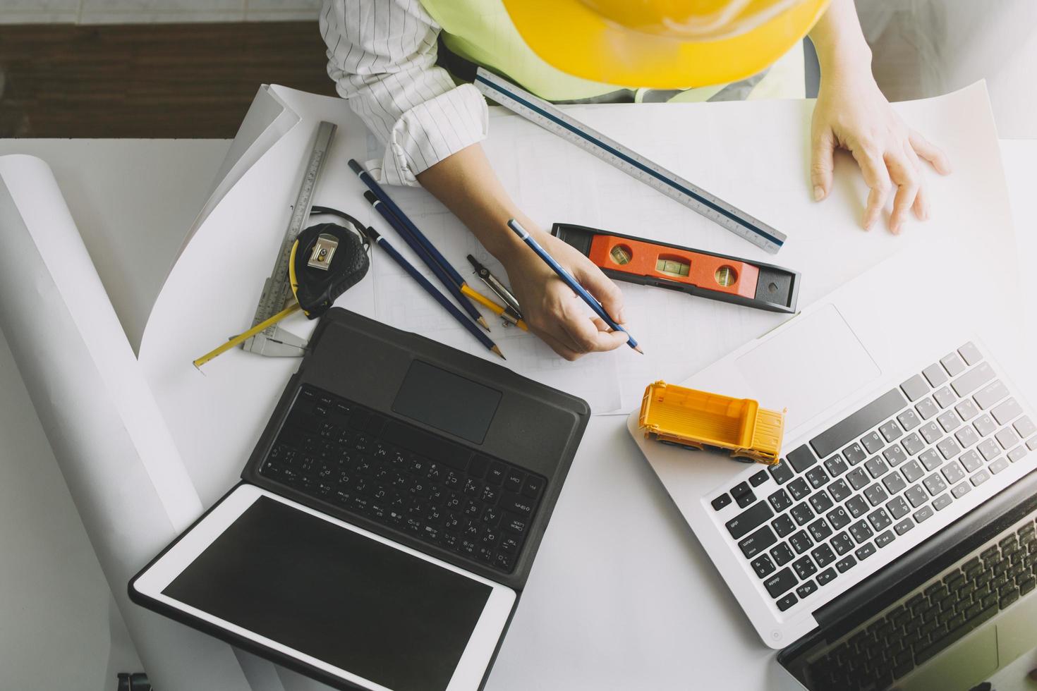 Two colleagues discussing data working and tablet, laptop with on on architectural project at construction site at desk in office photo