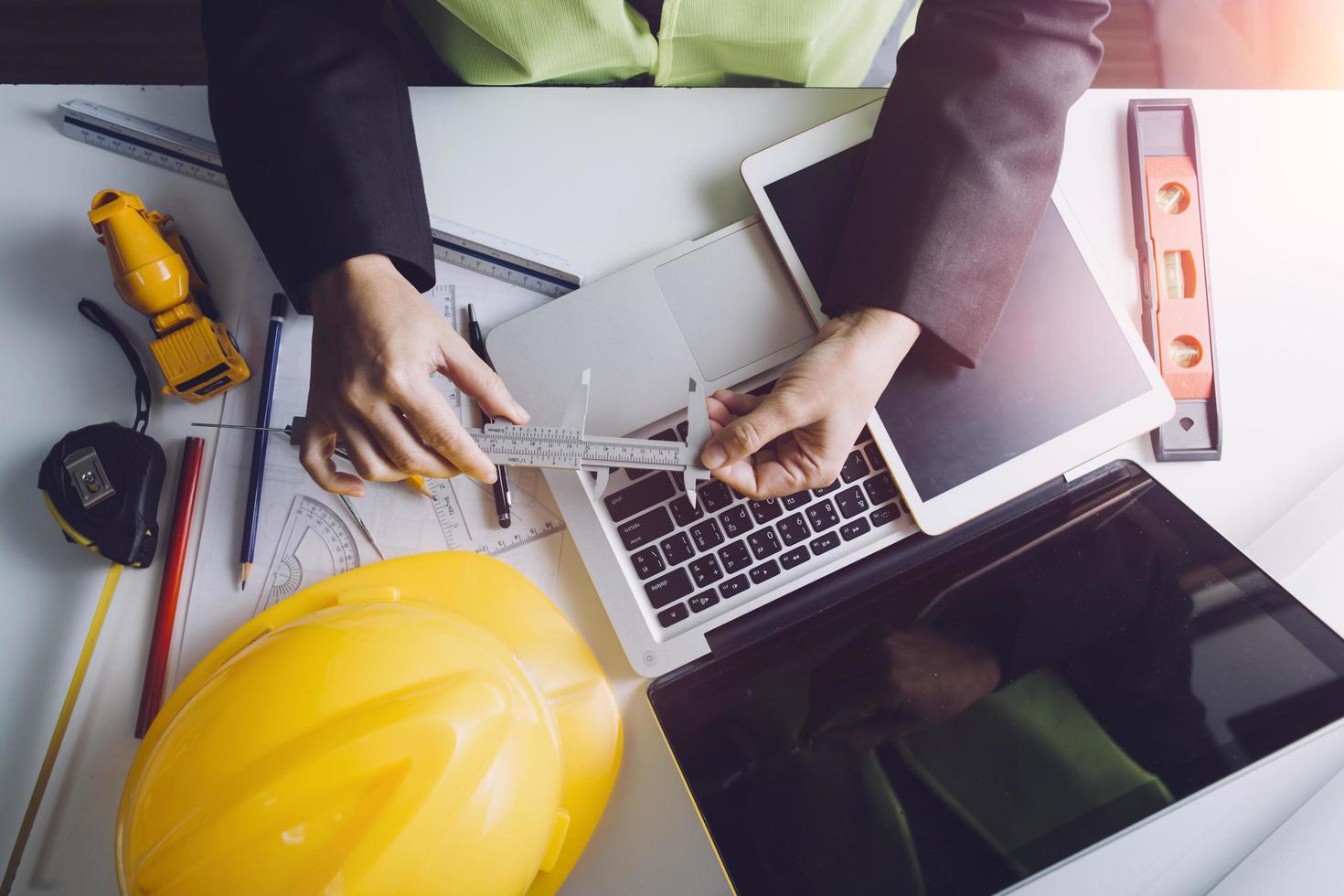Two colleagues discussing data working and tablet, laptop with on on architectural project at construction site at desk in office photo