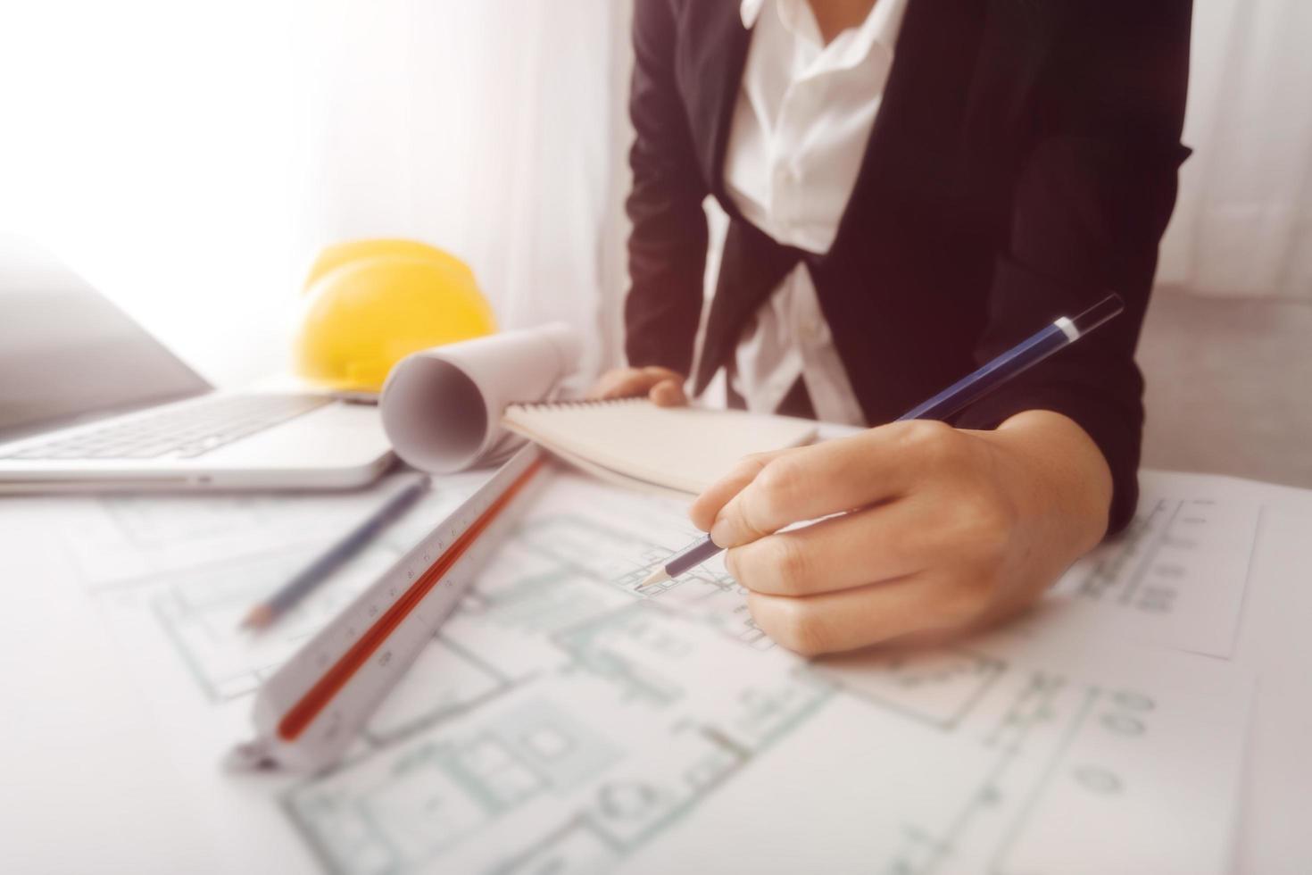 business hand working and laptop with on on architectural project at construction site at office desk in office photo