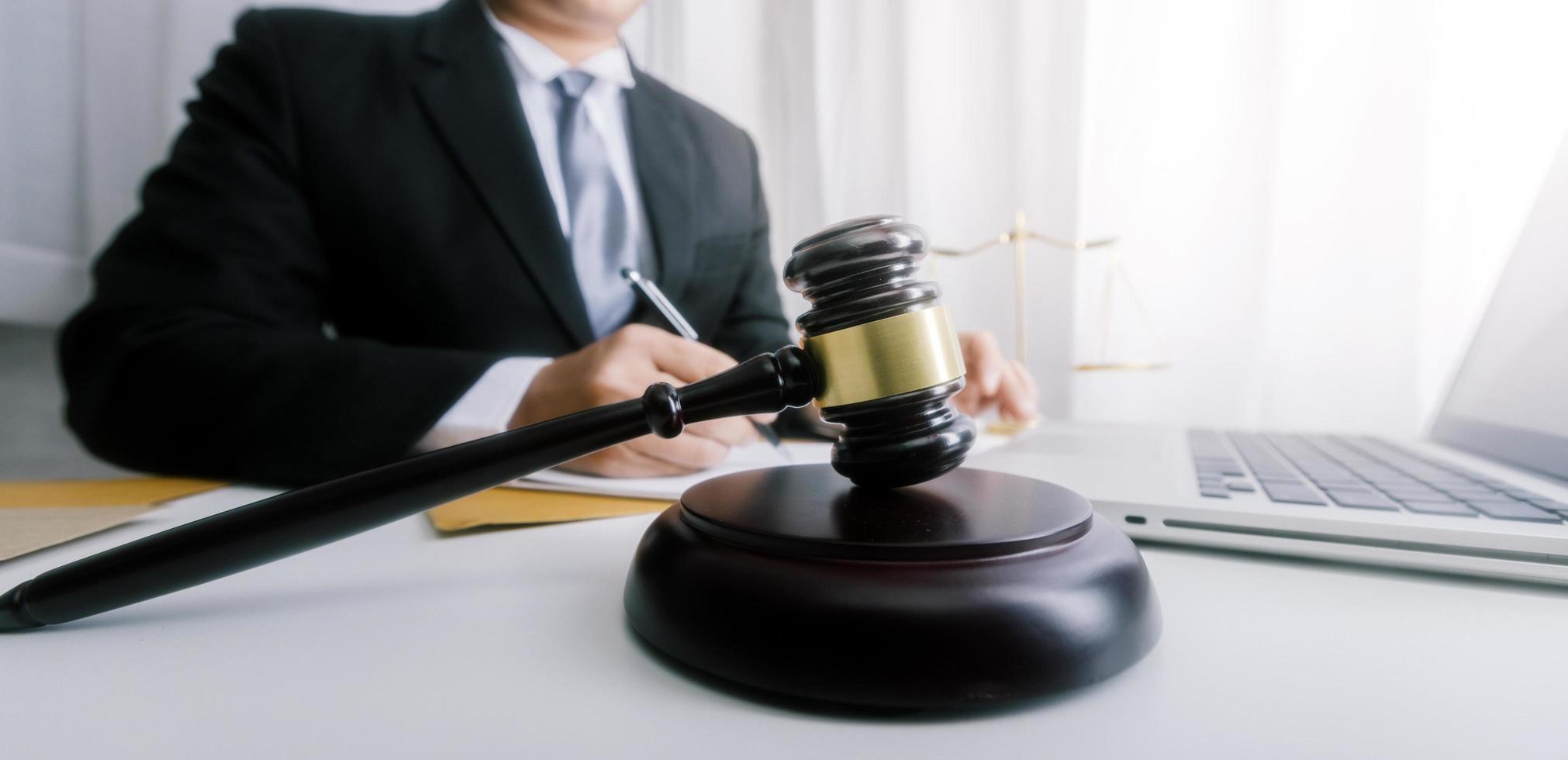 Justice and law concept.Male judge in a courtroom with the gavel, working with, computer and docking keyboard, eyeglasses, on table in morning light photo