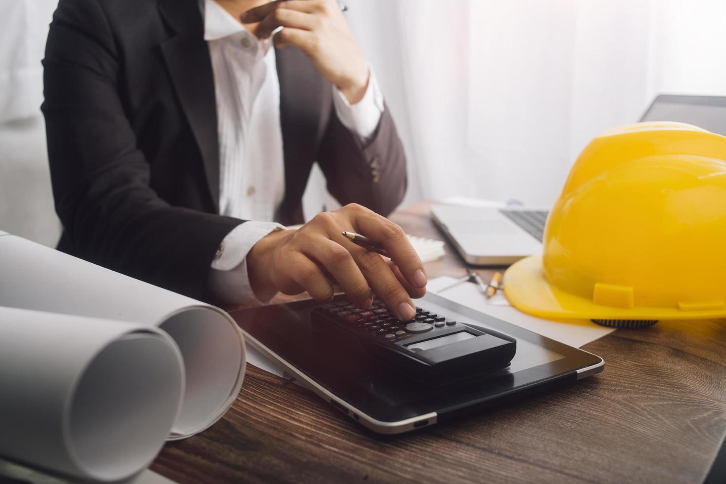 Two colleagues discussing data working and tablet, laptop with on on architectural project at construction site at desk in office photo