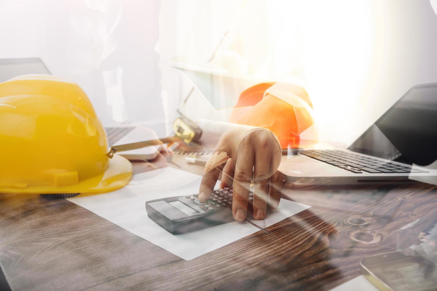 Two colleagues discussing data working and tablet, laptop with on on architectural project at construction site at desk in office photo