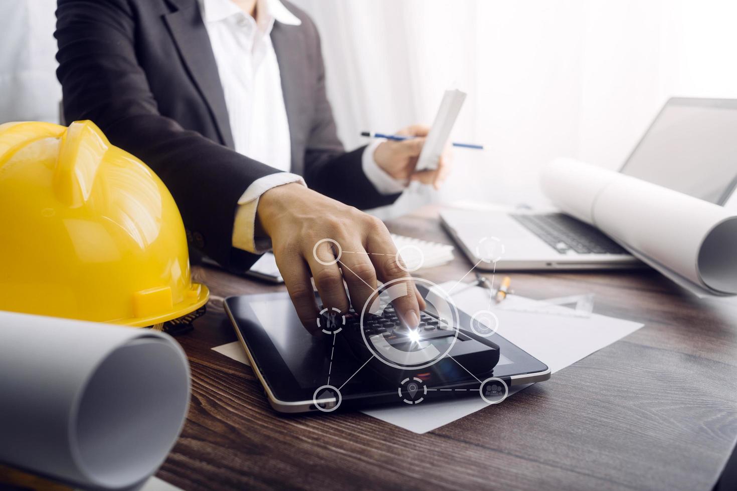 Dos colegas discutiendo el trabajo de datos y una tableta, un portátil con un proyecto arquitectónico en el sitio de construcción en un escritorio en la oficina foto