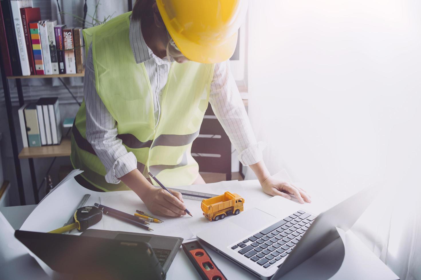 Two colleagues discussing data working and tablet, laptop with on on architectural project at construction site at desk in office photo