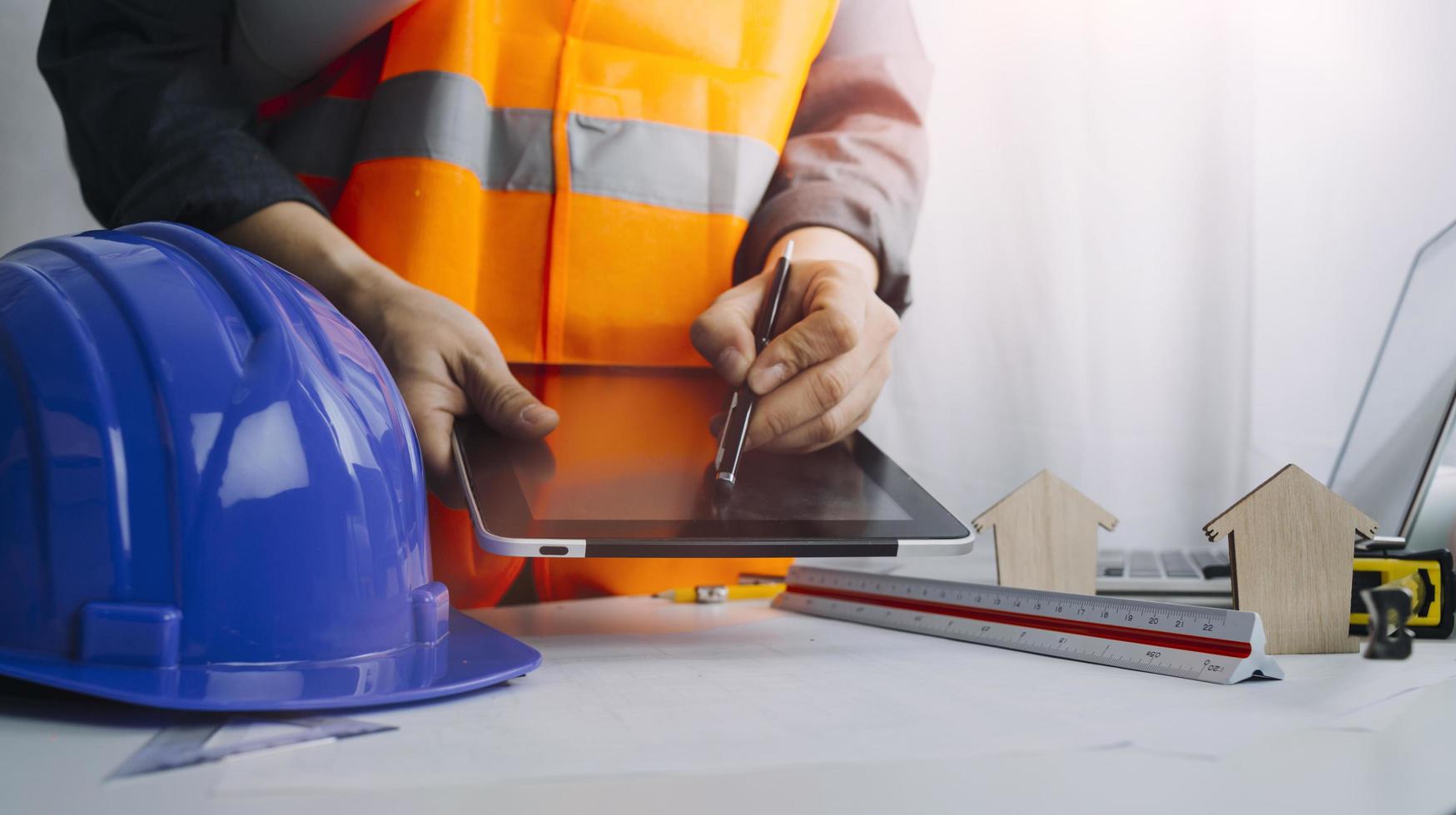 Two colleagues discussing data working and tablet, laptop with on on architectural project at construction site at desk in office photo