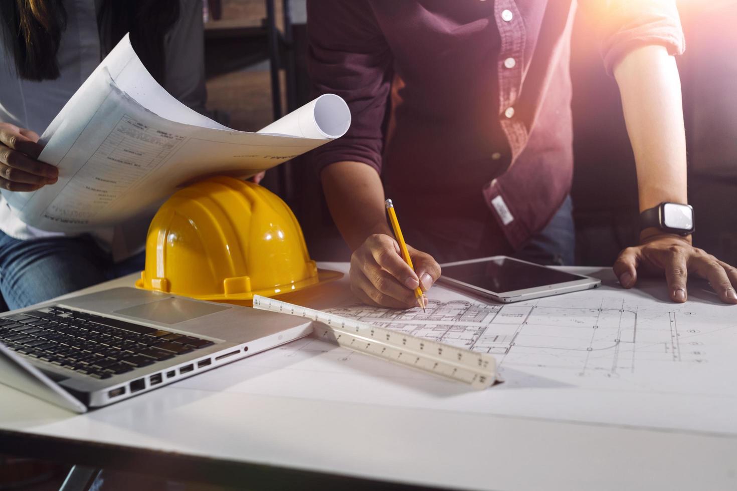 trabajo manual de negocios y computadora portátil con un proyecto arquitectónico en el sitio de construcción en el escritorio de la oficina foto