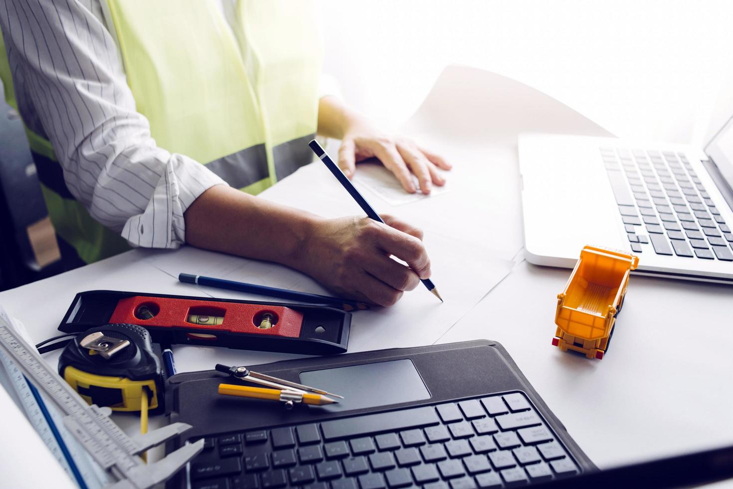Two colleagues discussing data working and tablet, laptop with on on architectural project at construction site at desk in office photo