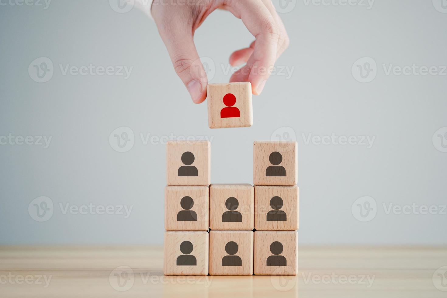 Human resources management and recruitment business hiring concept, corporate hierarchy, recruiter complete team by one leader person, professional staff research, hand hold red people icon on cube. photo