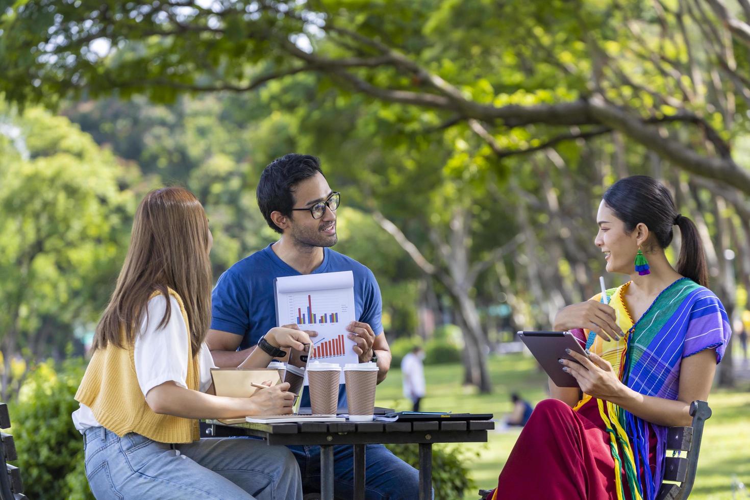 grupo de personas de negocios asiáticos que tienen un proyecto de reunión afuera en el parque público durante el verano para la educación universitaria y la lluvia de ideas foto