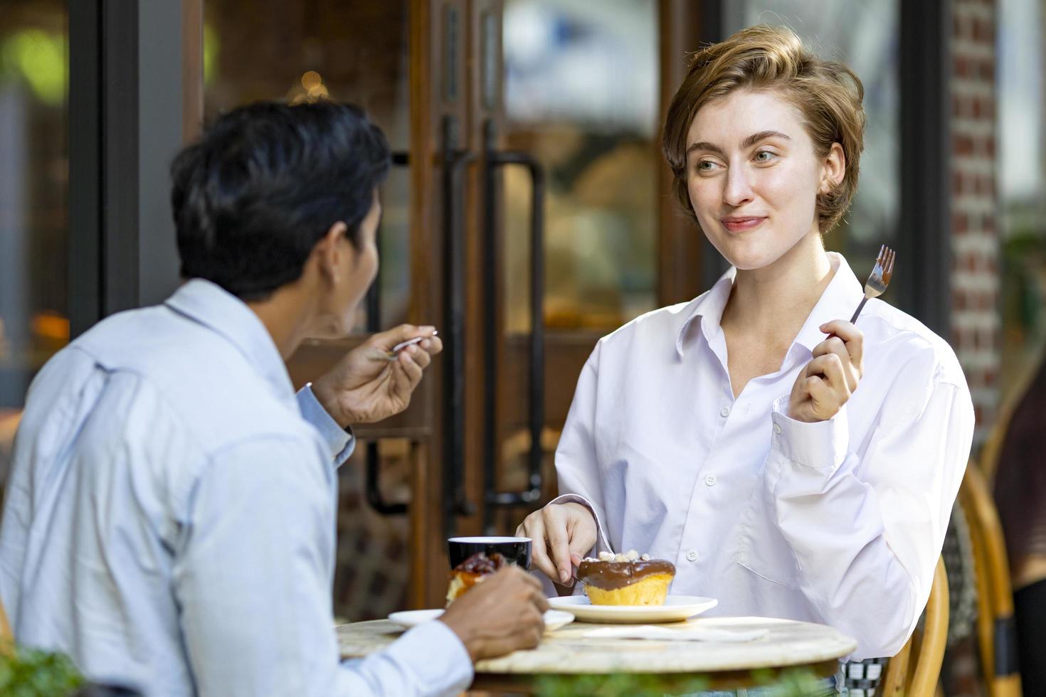 una pareja caucásica tiene una cita en un café bistró de estilo europeo disfrutando del ambiente matutino en la plaza de la ciudad con pasteles dulces y una taza de café foto