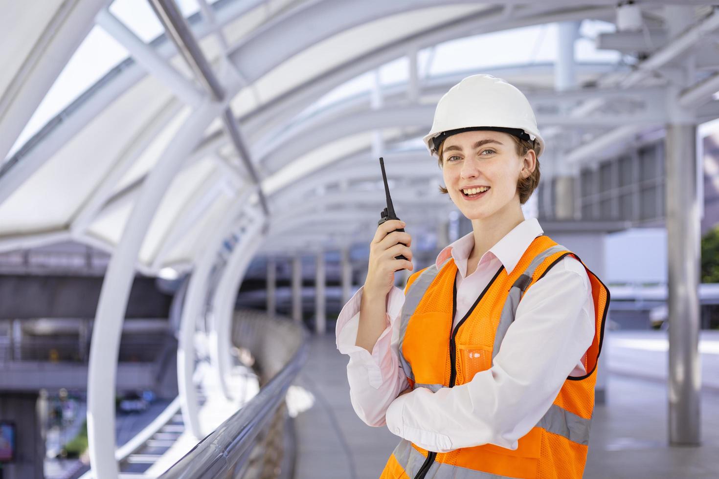 una ingeniera caucásica está usando walkie talkie mientras inspecciona el proyecto de construcción para la arquitectura moderna y el concepto de desarrollo inmobiliario foto