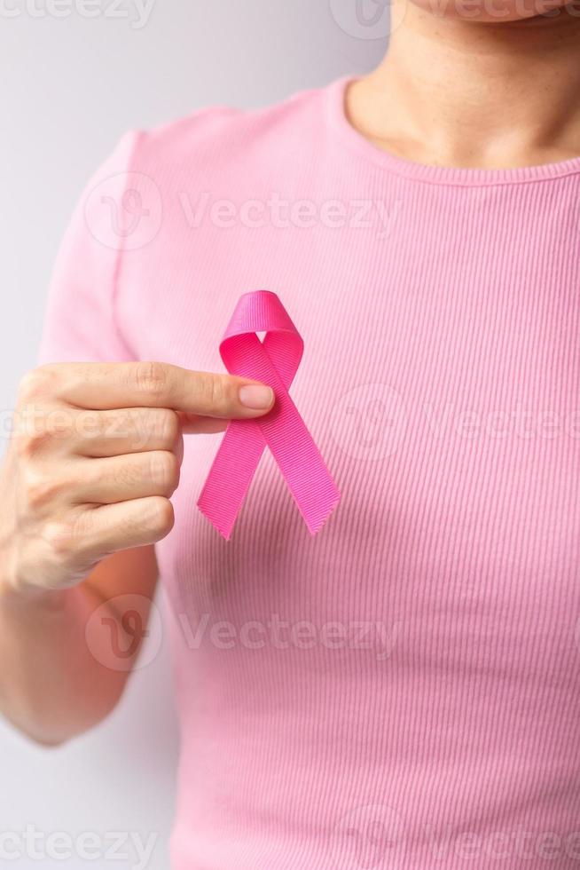 mes de concientización sobre el cáncer de mama de octubre rosa, la mano de la mujer sostiene una cinta rosa y usa una camisa para apoyar la vida y la enfermedad de las personas. concepto del mes nacional de los sobrevivientes del cáncer, la madre y el día mundial del cáncer foto