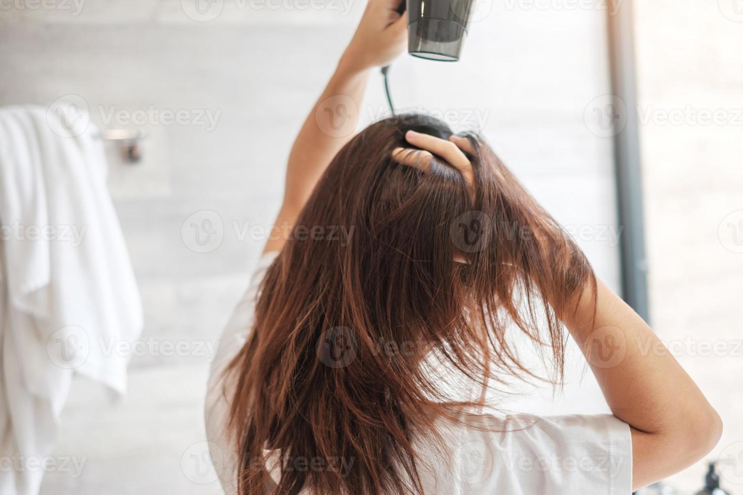 mujer joven que usa secador de pelo en casa o en el hotel. peinados y conceptos de estilo de vida foto