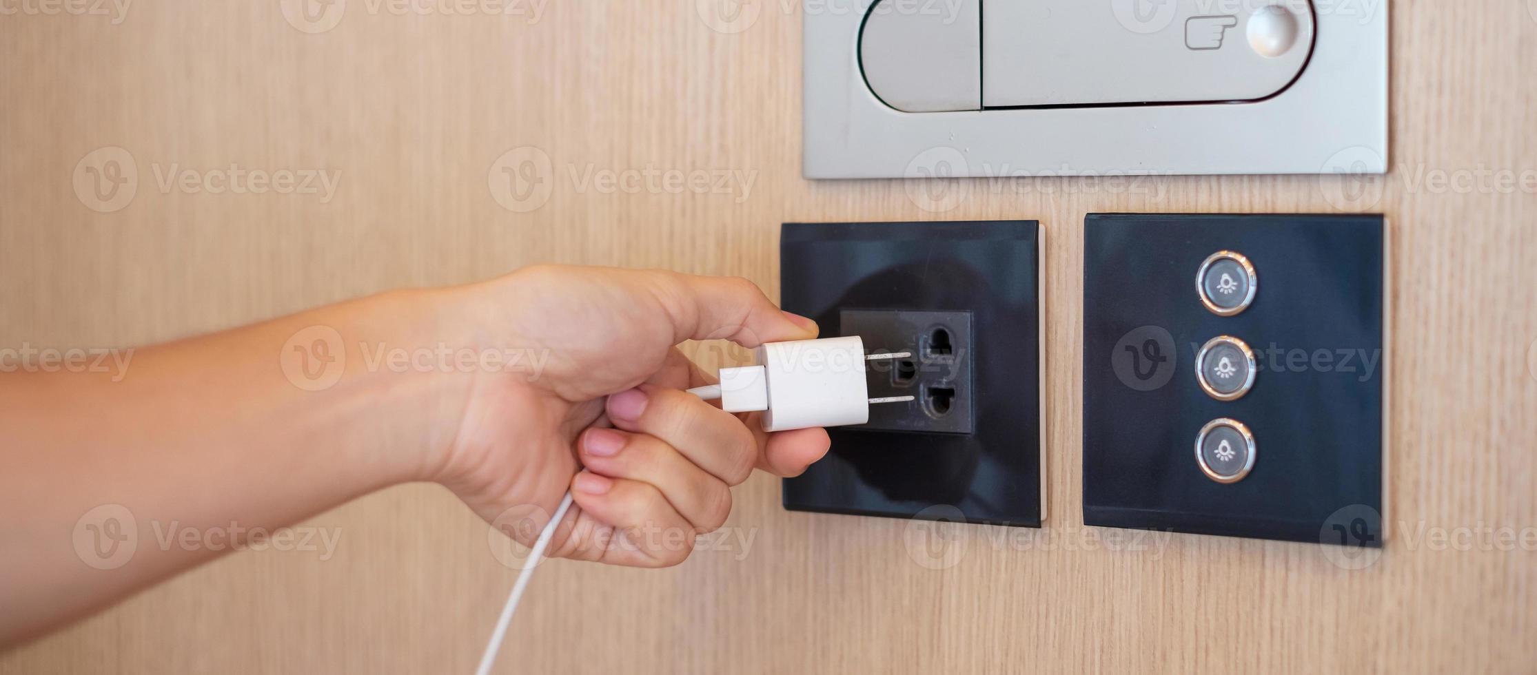 Closeup finger unplugging or plugging of electricity device at home. Energy Saving, power, electrical and lifestyle concepts photo