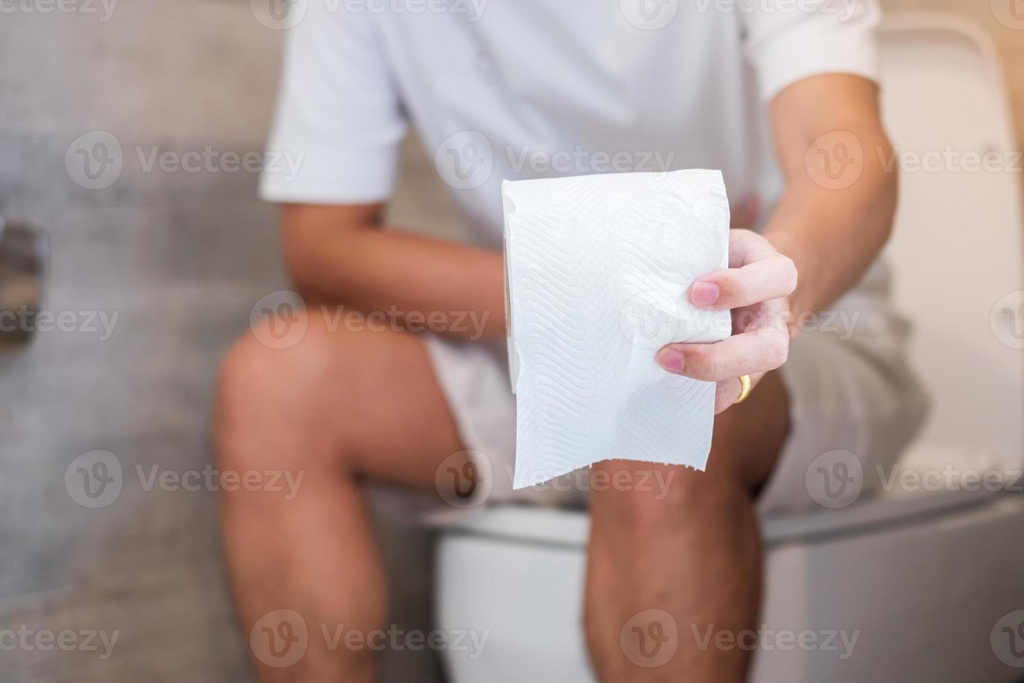 man holding toilet paper roll during sit on toilet bowl. diarrhea