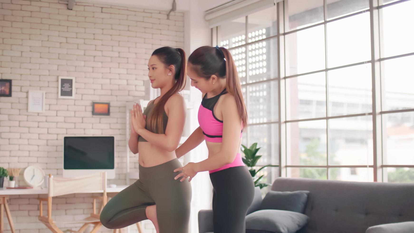 dos chicas asiáticas haciendo ejercicios de yoga en casa. foto