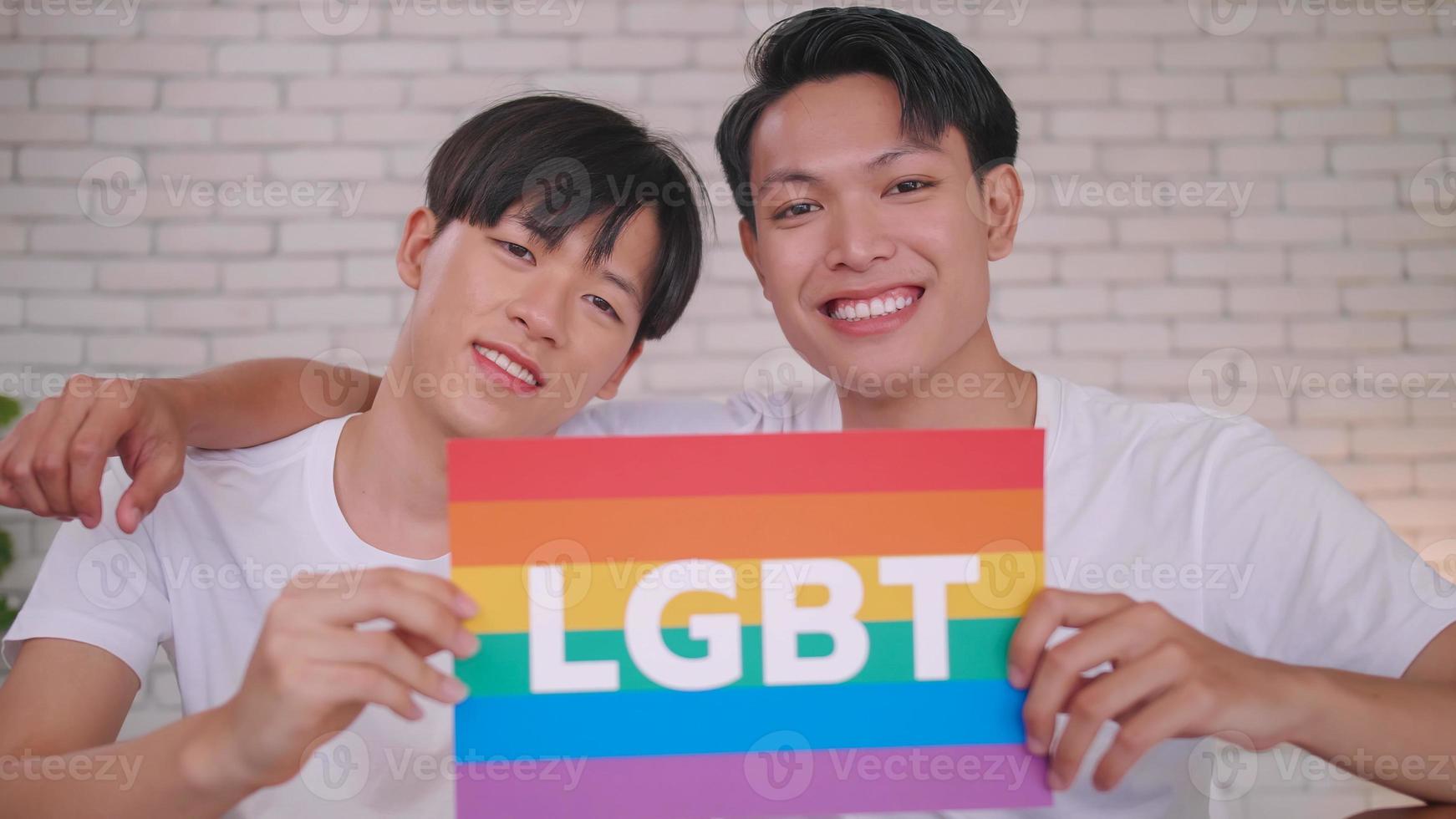 Happy gay Asian couple showing their love with rainbow flag. photo