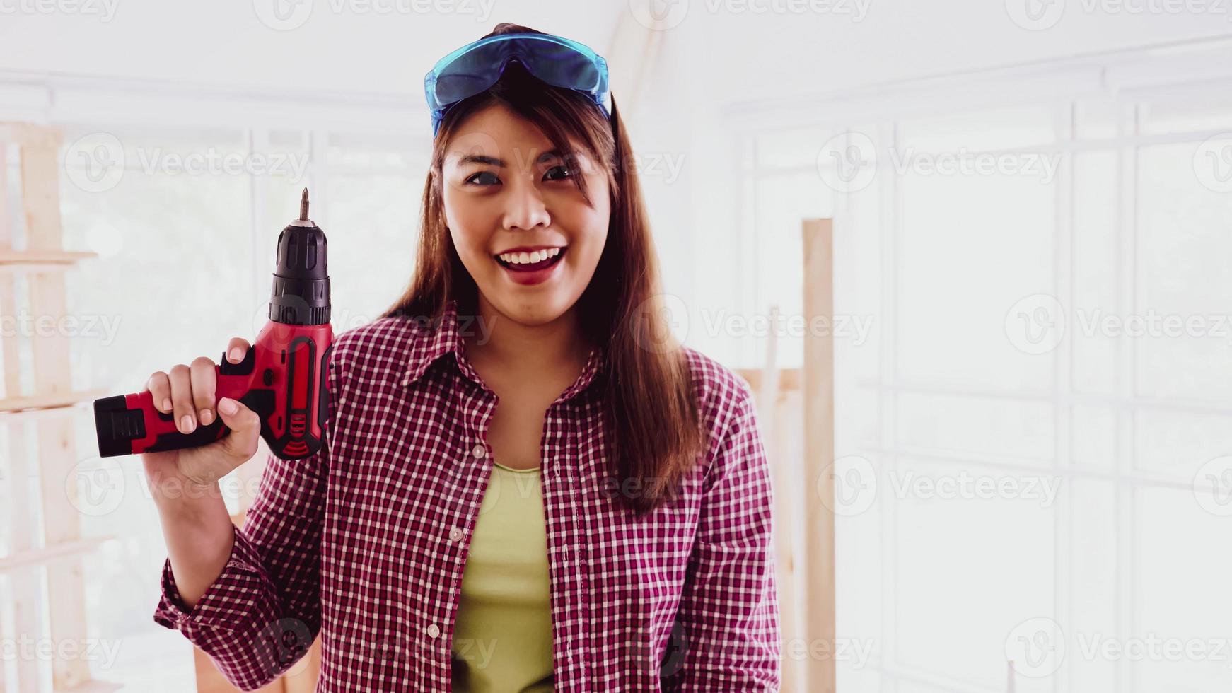 Happy female carpenter holding a drill at site. photo