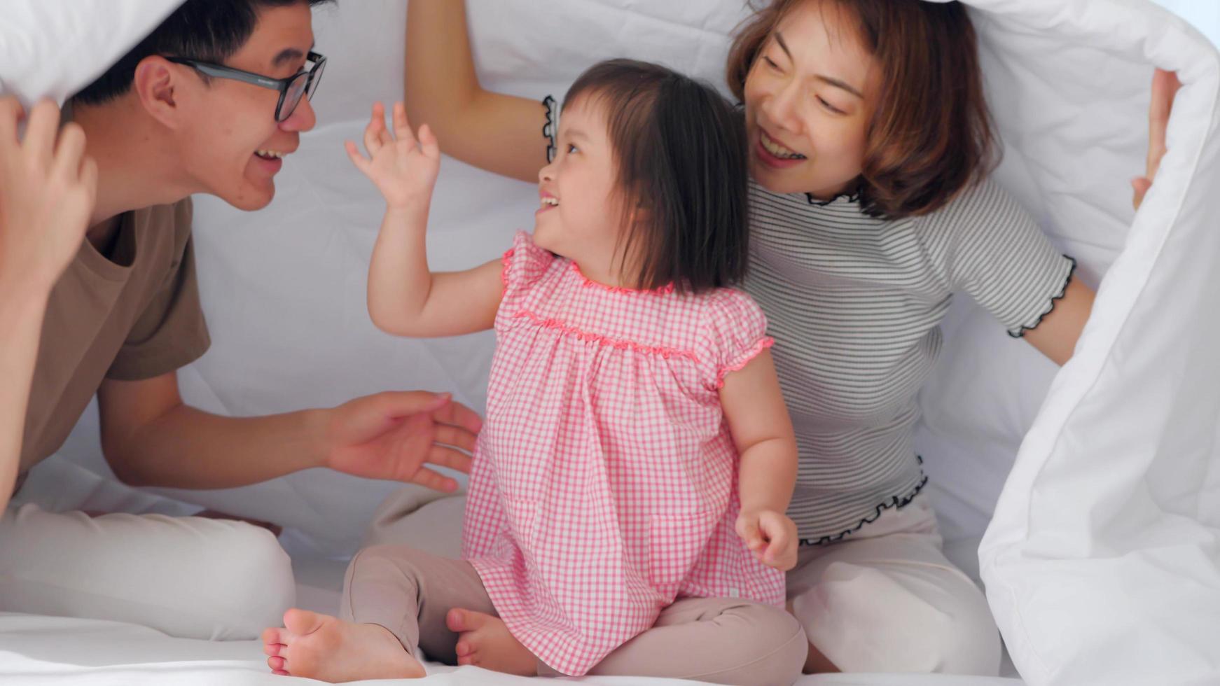 Happy family with mother, father and disabled daughter spending time together in bedroom. photo