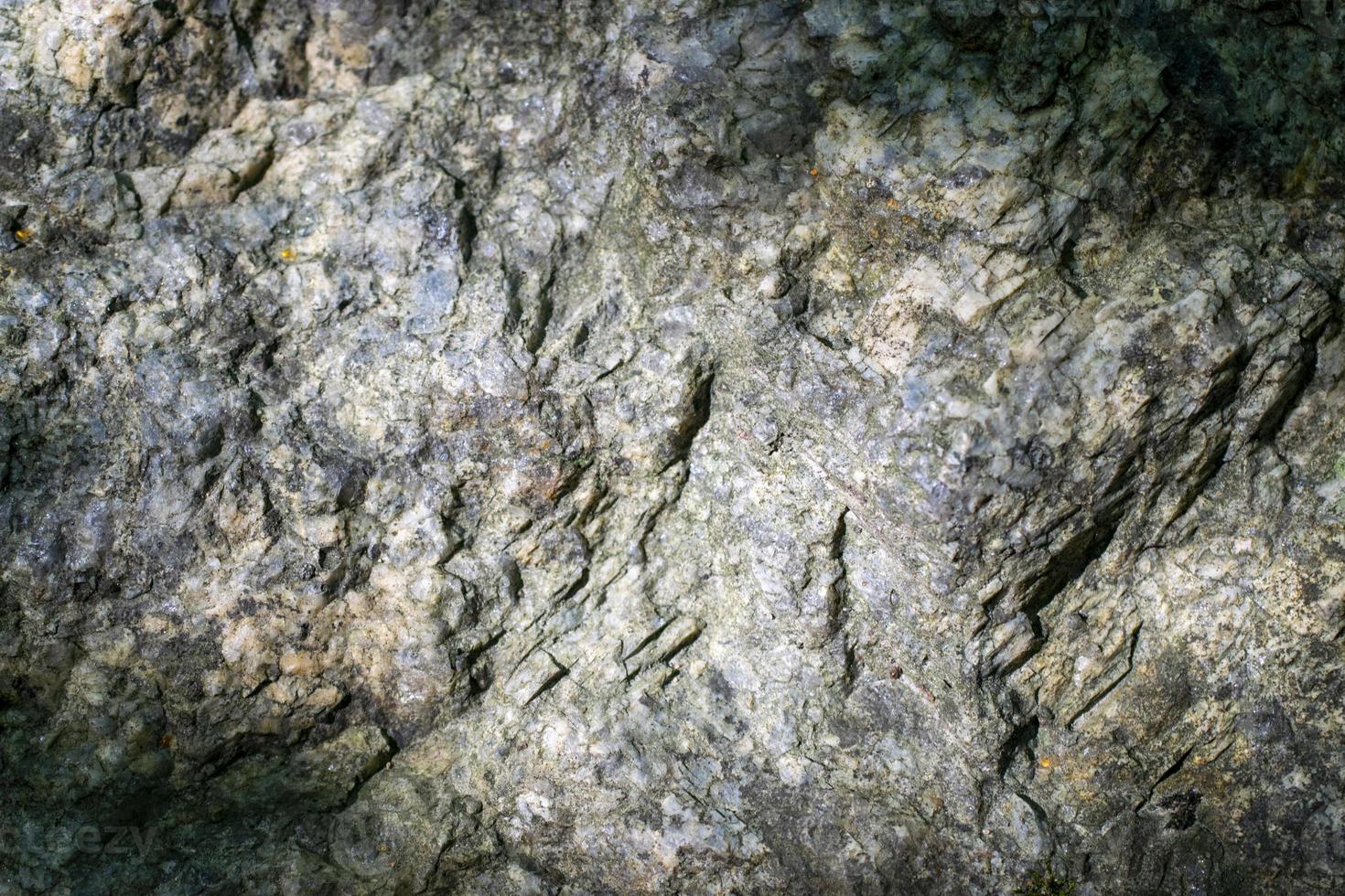 Raw granite rock texture background. Fragment of natural stone wall. photo