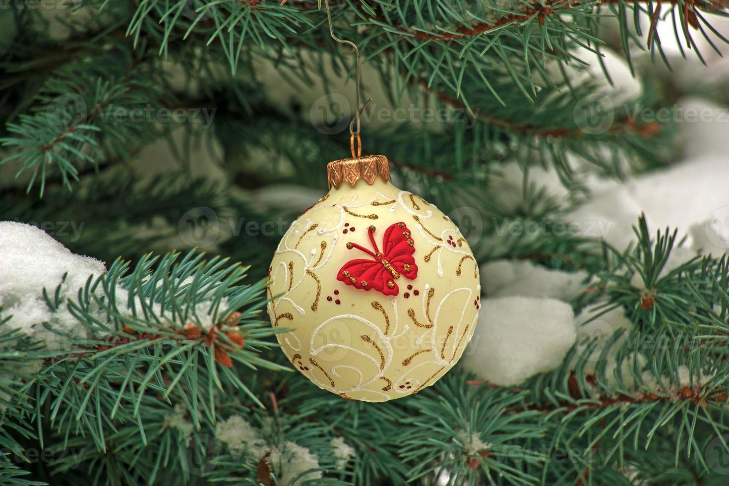 Christmas ball hanging on a snow-covered branch of a Christmas tree on a festive background of white snow and snowy bokeh with copy space photo