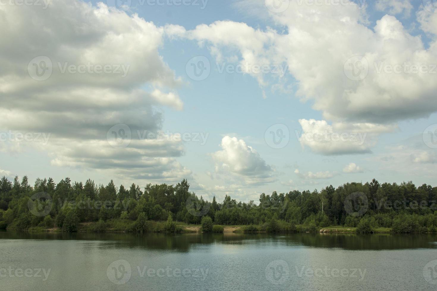 paisaje de verano con un hermoso lago con abetos contra un cielo nublado foto